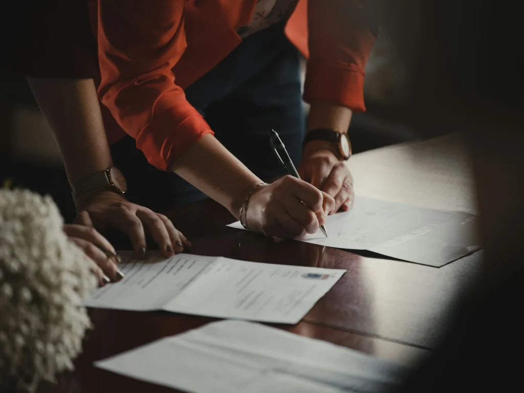 documents a person signing papers on a table